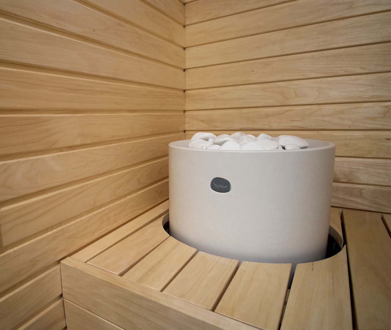 Valkoinen kiuas upotettuna lauteisiin.